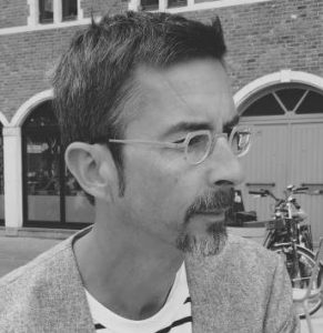Black and whote photo of man with beard and wearing round glasses looking to right