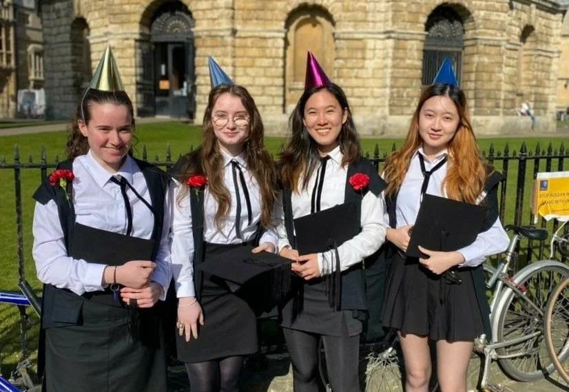 rown of four young women in subfusc in front of Radcliffe Camera